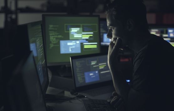 Egy férfi több monitoron dolgozik egyszerre a számítógépén