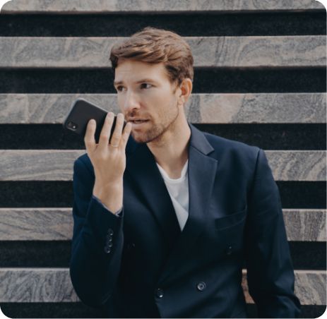 Mann im Anzug, der unterwegs die App "Sprache zu Text" auf seinem Handy nutzt