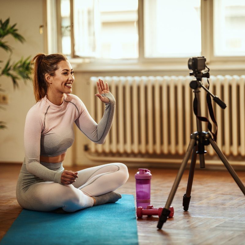 Woman recording her fitness class with a camera on a tripod